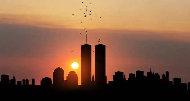 Photo of New York skyline silhouette with Twin Towers and birds flying up like souls at sunset. American Patriot Day banner.