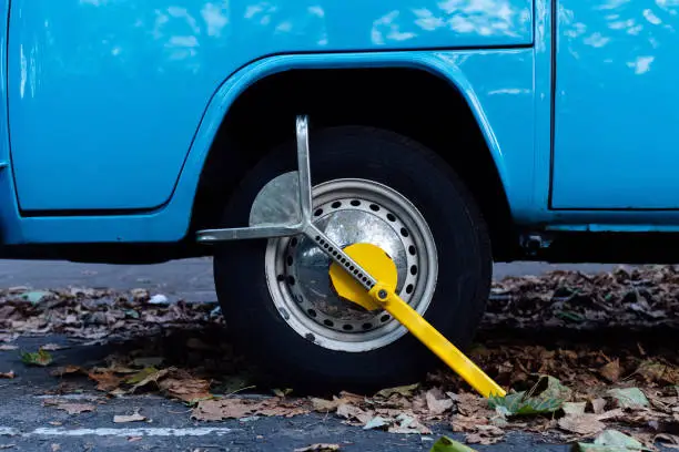 Cropped Image Of Classic Vintage Blue Van Clamped On Street because illegal parking violation