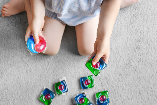 child playing with laundry capsules, washing gel capsules. Keep household chemicals away from children