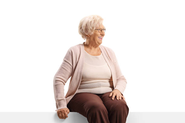istock Happy elderly woman sitting on a blank panel and looking to the side 1417940860