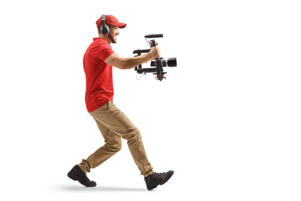 Full length profile shot of a camera operator using a stabilizer and recording with camera isolated on white background