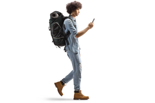 istock Full length profile of a male backpacker walking and using a smartphone 1417940891