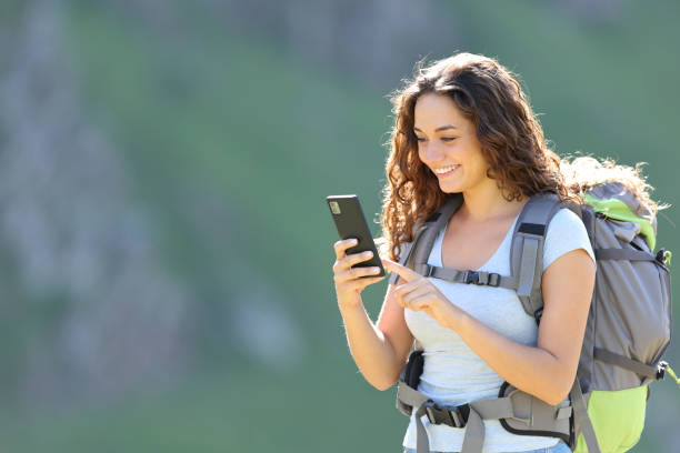 istock Happy hiker consulting smartphone while trekking 1417945104