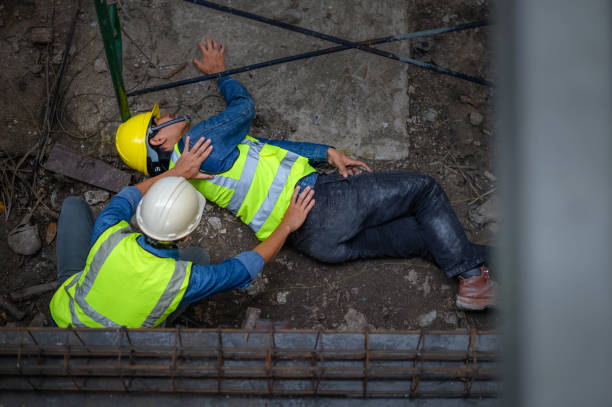 a young asian builder falls from a scaffold at a construction site. an engineer supervising the construction came to the aid of a construction worker who fell from a height with hip and leg injuries. - wrong injury imagens e fotografias de stock