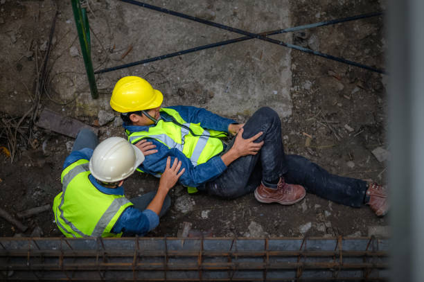 un giovane costruttore asiatico cade da un'impalcatura in un cantiere. un ingegnere che supervisionava la costruzione è venuto in aiuto di un operaio edile che è caduto da un'altezza con lesioni all'anca e alle gambe. - lesionato foto e immagini stock