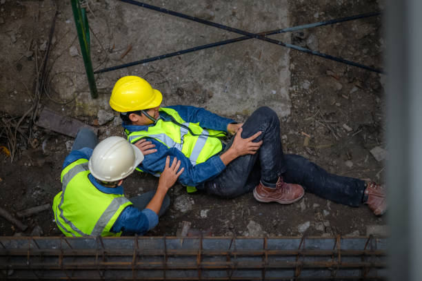 젊은 아시아 건축가가 건설 현장의 비계에서 떨어집니다. 공사를 감독하는 엔지니어가 엉덩이와 다리 부상으로 높이에서 떨어진 건설 노동자의 도움을 받았다. - body construction 뉴스 사진 이미지