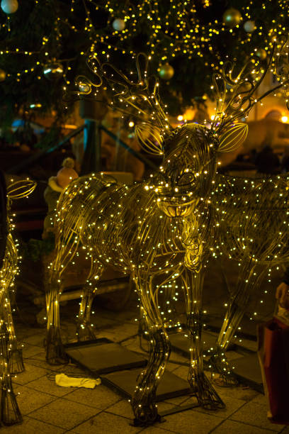 Closeup of Christmas pine tree with blurred garland lights and silhouette of reindeer as Christmas tree decoration. New Year holiday background