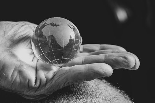 old woman holding a glass globe in her hands, black and white photo, the world is in mom's hands