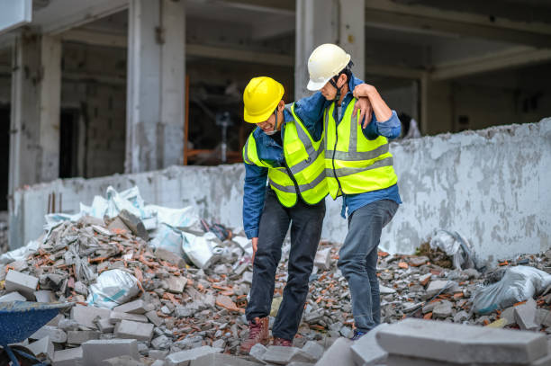 los supervisores de construcción o ingenieros ayudan a los trabajadores de la construcción que tienen lesiones en las rodillas y las piernas, causadas por accidentes en el sitio de construcción. - accident occupation physical injury construction fotografías e imágenes de stock