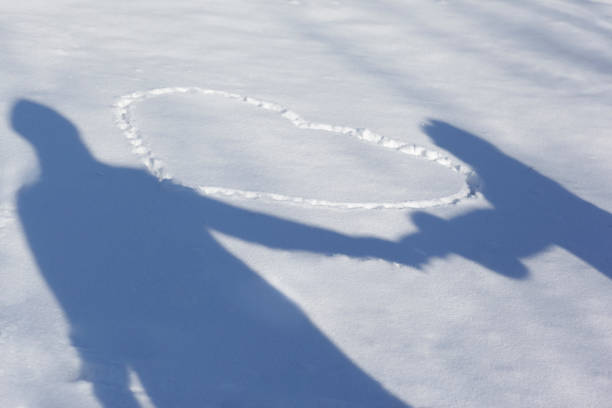 Sunny day shadow companions on a snowy day with a heart written in the snow