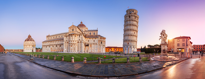 Pisa, Italy - December 17, 2021: The Leaning Tower of Pisa in the Square of Miracles at twilight. The 12th century cathedral is known for its bell tower which displays a nearly four-degree lean.