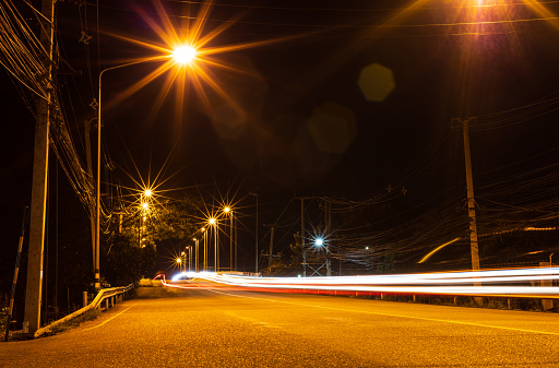 The scenery, the street lamps shine bright orange with flares and headlights at night, and many poles and power lines are common in Thai cities.