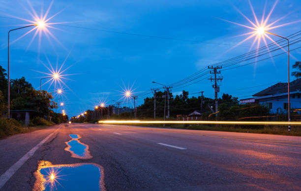 lo scenario delle lanterne che brillano di arancione contro il cielo blu al mattino presto. - street light fog morning country road foto e immagini stock