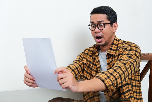 Asian man read a letter with shocked expression