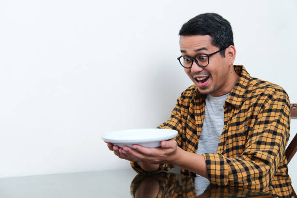istock Asian man looking to empty dinner plate that he hold with amazed expression 1417954942