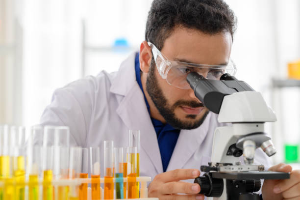 Portrait of scientist looking in microscope while working on oil chemistry stock photo