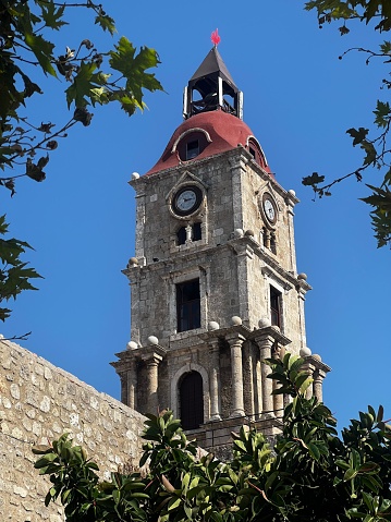 A medieval clock tower surrounded by trees in Rhodes town