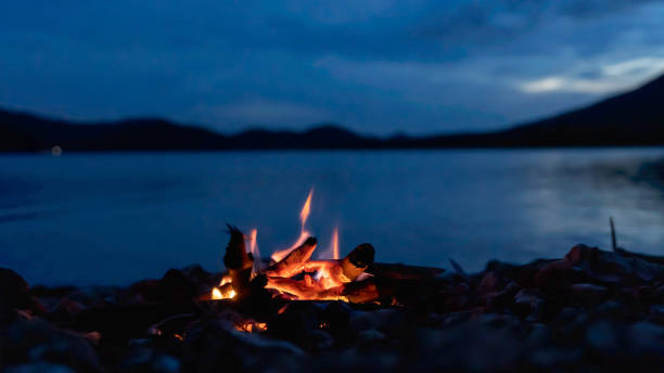 istock Small campfire with gentle flames beside a lake during blur hour. 1417962572