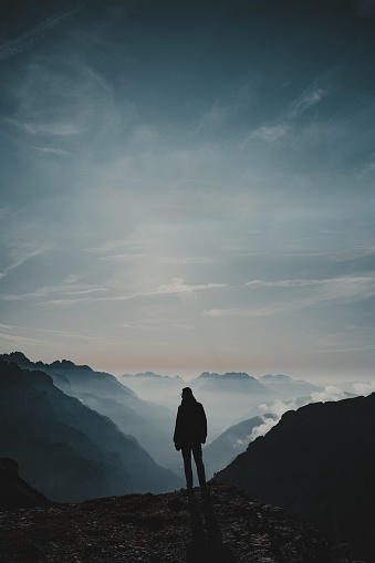 A vertical shot of a man looking out over the Dolomites in Italy