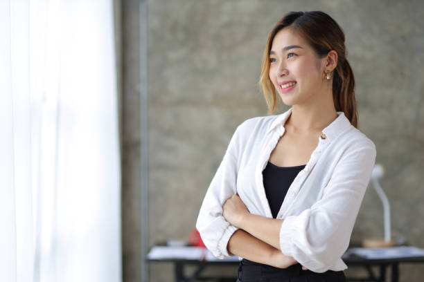 Portrait of a charming Asian businesswoman standing looking away contemplating and imagining success. stock photo