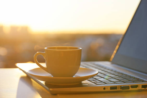 istock Coffee or tea cup on laptop against the window with sunshine 1417970079