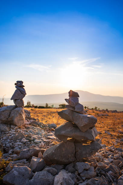 stone stack with balanced stones on blurred mountain background in sunset warm light stock photo - stacking stone rock full imagens e fotografias de stock