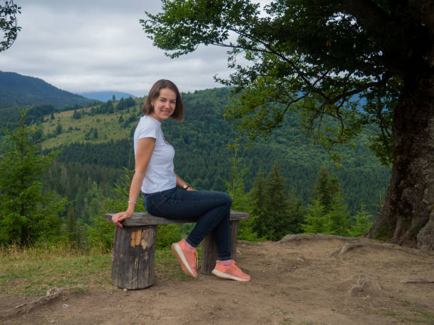 istock Female in casual clothes sits under large tree with forest background 1417970914