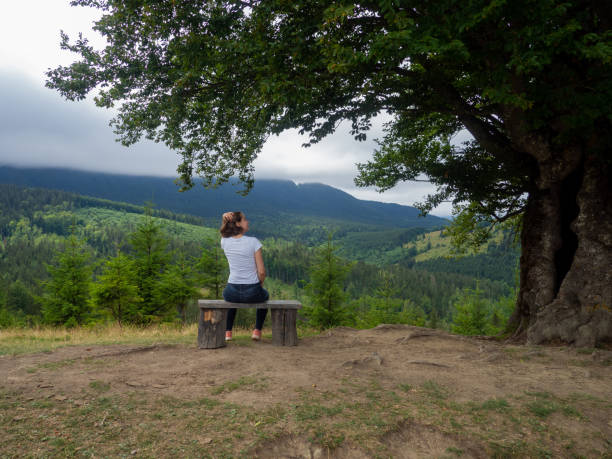 istock Female in casual clothes sits under large tree with forest background 1417971084