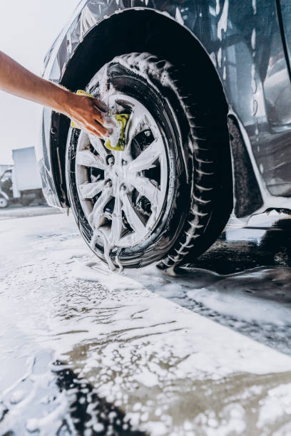 A man washes his car with foam at a self-service car wash, wheels and tires close-up A man washes his car with foam at a self-service car wash, wheels and tires close-up. porous sponge stock pictures, royalty-free photos & images