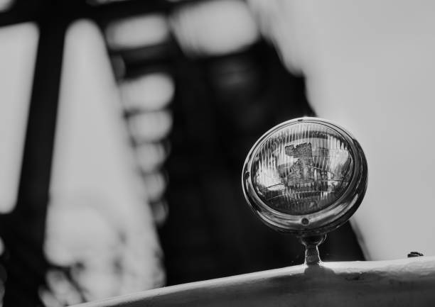 A grayscale closeup shot of a round light on a car