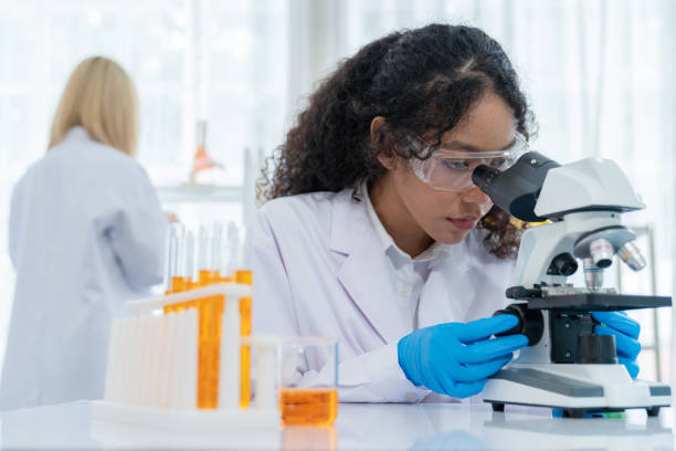 istock Young scientist looking through a microscope in a modern laboratory. Medical science looking at sample on the glass plate. Research and development concept. Work with high technology 1417977899