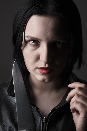 serious young woman with knife looking at camera closeup portrait