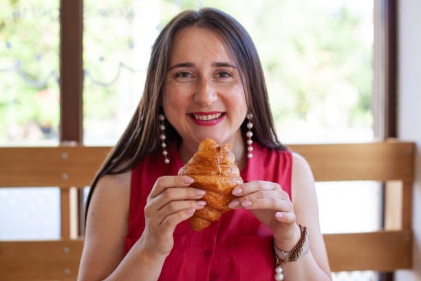 istock Young beautiful woman eating croissant 1417978080