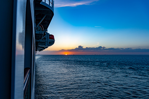 Sunset from a cruise ship off Stavanger, Norway, Europe. The P&O cruise liner Iona is heading towards the Norwegian port of Stavanger via the North Sea. This is a view from a balcony towards the stern at sunset with the sun on the horizon.