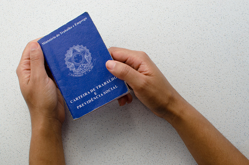 Flatlay shot of a black passport with a smartphone that has a digital illustration of Covid-19 digital health vaccination passport on top of a brown wood backgrounds.