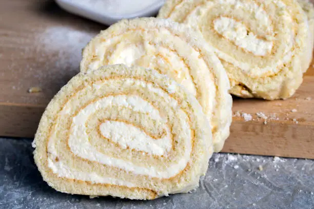 a rolled roll of soft cake and sweet curd filling, white sugar and a sweet dessert made of dairy products