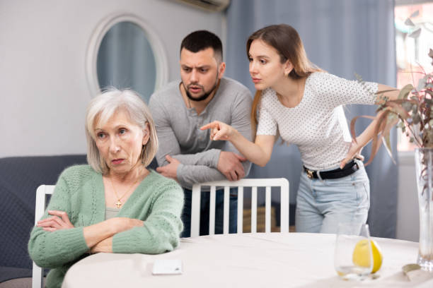 Old woman ignoring her daughter and son-in-law arguing with her Old woman ignoring her daughter and son-in-law standing behind and arguing with her at home. mother in law stock pictures, royalty-free photos & images