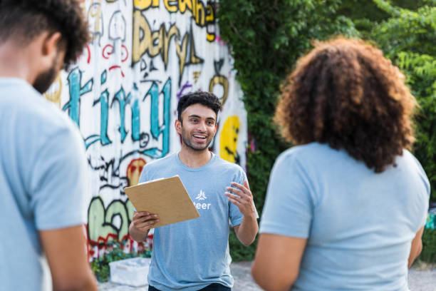 Young adult male volunteer coordinator explains graffiti clean-up project