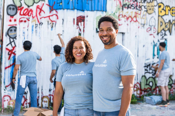 istock As volunteers work in the background, couple smiles for camera 1417985976