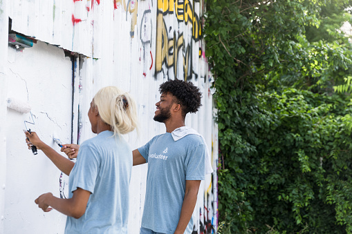 Two siblings enjoy volunteering together as they paint over the graffiti at their park.