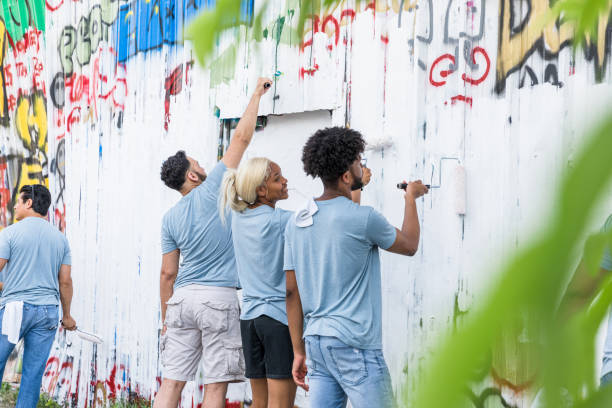 istock Multiracial group volunteers paint over graffiti at park 1417986056