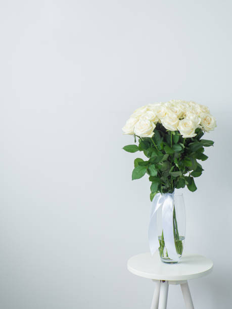 beau bouquet de roses blanches en fleurs dans un vase en verre sur table ronde - hybrid tea rose photos et images de collection