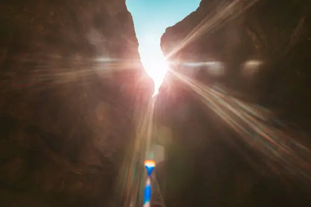 Photo of rays of the sun, beautiful sunlight in a gorge in the mountains early in the morning.beautiful weather with a blue sky peeking out from behind the rocks and a gentle yellow sun blinding your eyes.