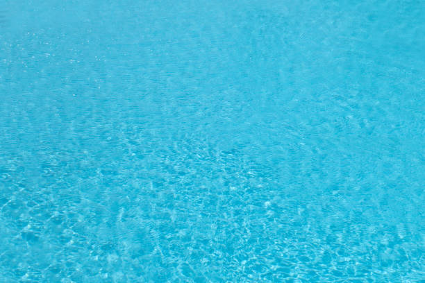 Blue pool water with solar reflections, transparent and clean, slightly heated by sunlight and not cold