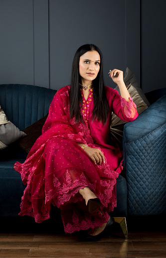 Portrait of beautiful Indian woman sitting on sofa at home