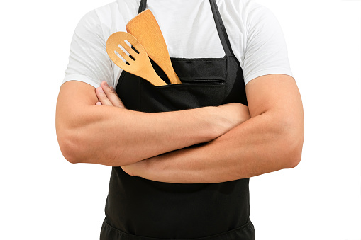 Torso of a chefs in a black apron with crossed arms isolated on a white background. Cooking concept.