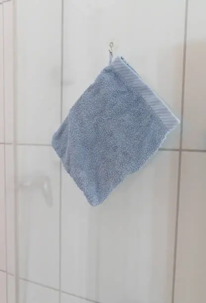 a blue washcloth is hanging in a bathroom on a glass door