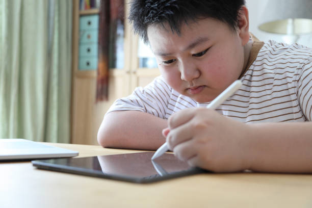 Drawing on Tablet The Asian boy drawing picture on the tablet. overweight boy stock pictures, royalty-free photos & images