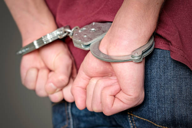 Arrested man in handcuffs with hands behind back. The criminal is in the police station. Arrested man in handcuffs with hands behind back. The criminal is in the police station restraining device stock pictures, royalty-free photos & images