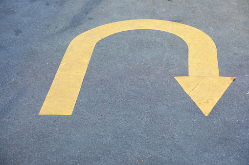 Yellow u-turn arrow sign on street